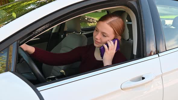 An otherwise friendly teenager talks on her cellphone in a car.  She gives a passerby a quick nasty