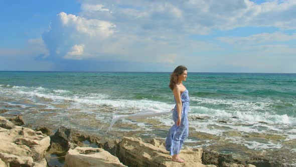 Happy Woman Standing on Rocky Beach, Enjoying Ocean Breeze, Waves Coming Ashore