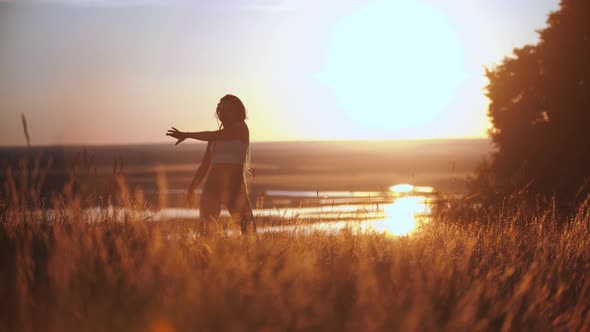 Woman with Long Blue Braids Dancing on Sunset Field
