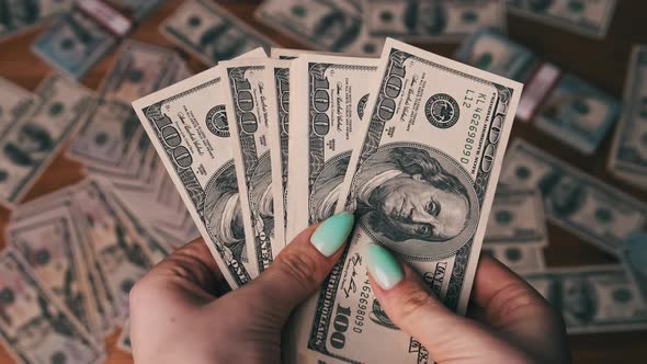 Dollars in Woman Hands on Background of Table with Money