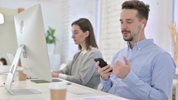 Creative Male Professional Listening To Music on Smartphone in Office