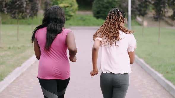 Young Active African American Female Friends Jogging in Park To Keep Healthy