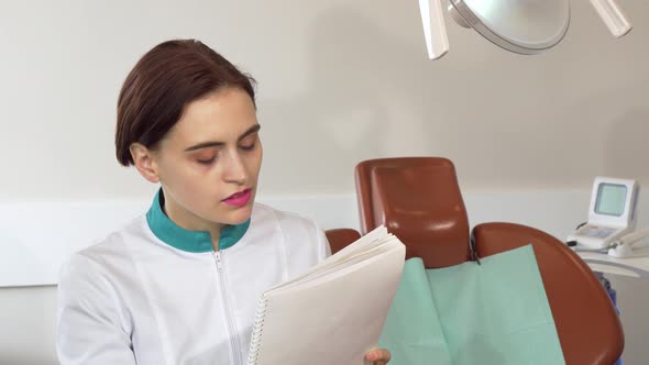 Charming Female Dentist Working at Her Office, Filling Medical Papers