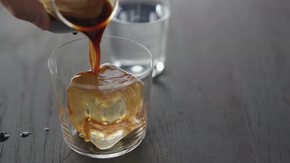 Slow Motion Making Espresso Tonic in Tumbler Glass Pour Espresso Over Ice Cube