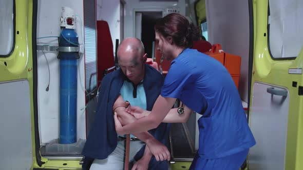 Man in Oxygen Mask Sit in Ambulance Car at Night with Nurse