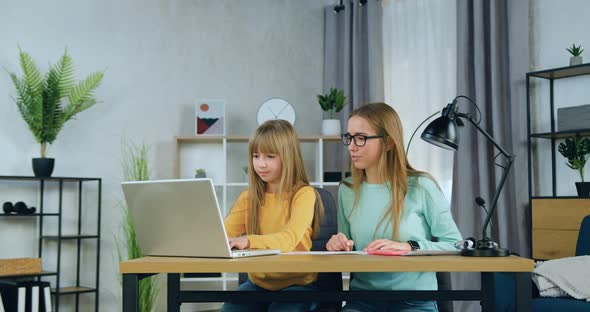 Sisters Sitting in front of Computer while Eldest Sister Helping with School home