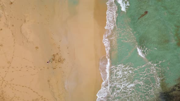 Aerial bird eye view of turquoisewater and beach. Woman walking on the sand