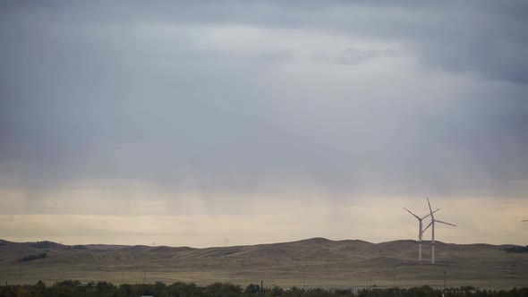 Motion the Blades of a Large Wind Turbine in a Field Against a Background of Orange Sunset on the