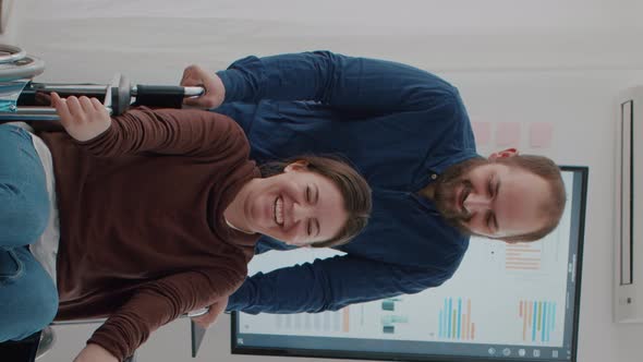 Video Vertical Cheerful Young Man Pushing Wheelchair with His Disabled Paralysed Coworker