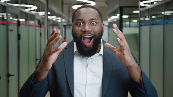 A Surprised and Shocked African American Businessman Looking at the Camera Against the Background of