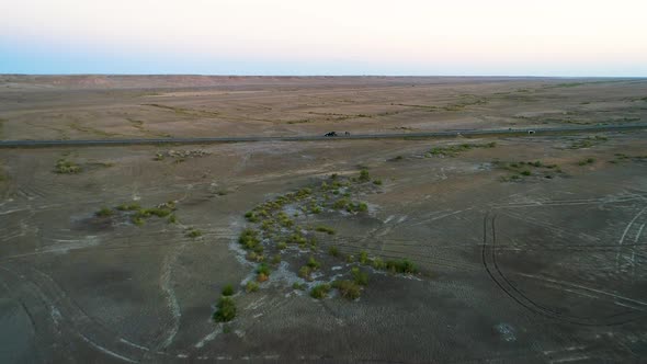 Aerial View of Car Driving on an Empty Road in the Middle of the Arid Desert.