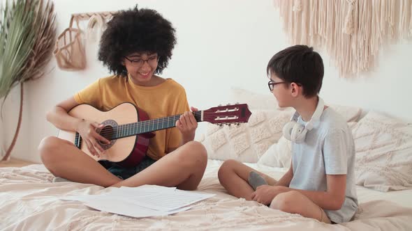 Funny Couple Playing Guitar While Sitting on Bed