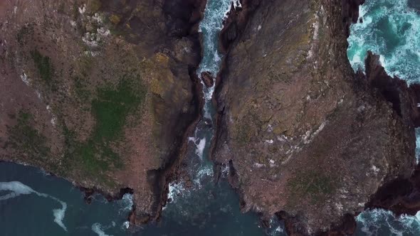 Birds-eye-view of a crevice separating two small rocky islands. Drone-shot.