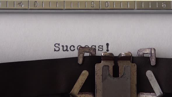 Typing word Success ! on retro typewriter. Close up.