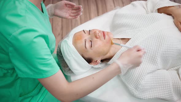 Girl Beautician Makes Facial Cleansing Procedure for Young Woman in Beauty Salon