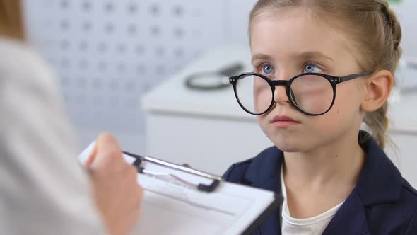 Female Child Looking at Optometrist Filling Patient Card, Eyesight Examination