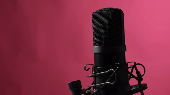 The Microphone is Spinning Against a Pink Background