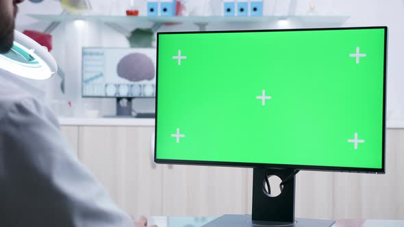 Static Over the Shoulder Shot of Doctor Working on Green Screen Mockup Computer