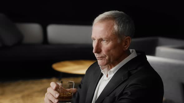 Mature Businessman Drinking Strong Alcohol Sitting In Modern Office