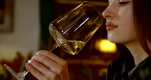 Young Pretty Woman Is Sipping White Wine From Glass in Restaurant