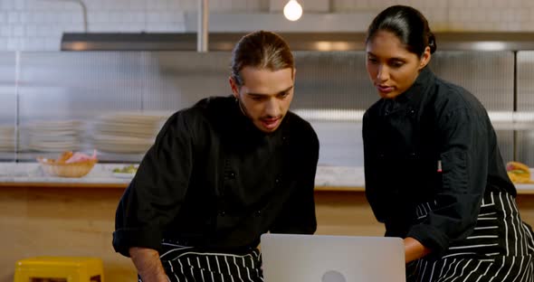 Male and female executive discussing over laptop 4k