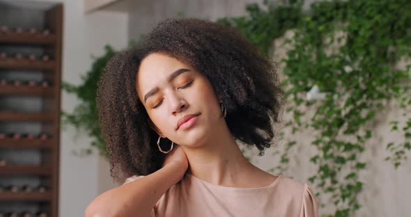 Closeup Portrait of African American Woman with Sad Expression on Her Face Holds Her Neck with Her