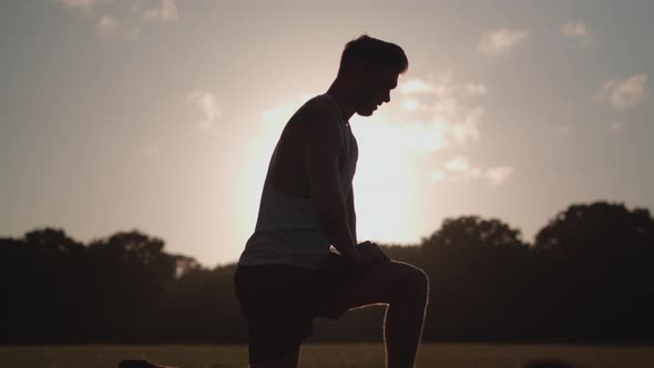 Man Stretchs His Legs In Park Before He Goes For a Run