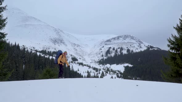 A Man with a Backpack Travels in the Mountains in Winter