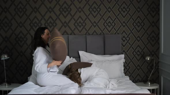 Woman with Daughter Having Pillow Fight on Bed