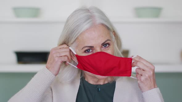 Portrait of senior caucasian woman putting on a red face mask and adjusting mask