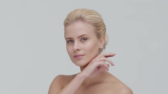 Studio portrait of young, beautiful and natural blond woman applying skin care cream. F