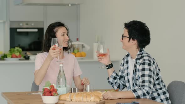 Female Lesbian Couple Eating at Table Having Healthy Lunch on Kitchen and Drinking Wine Rbbro