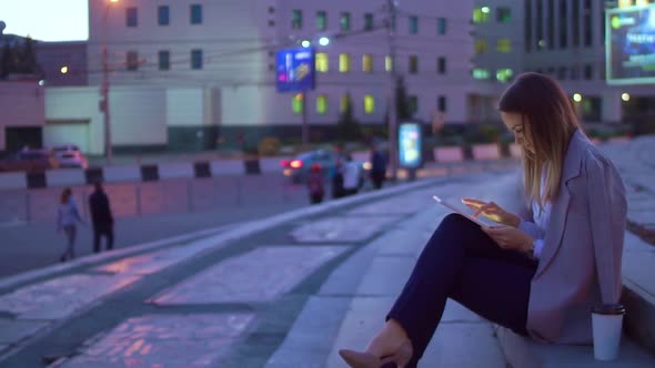 The Girl Works in the Tablet, in the Evening in the City Center