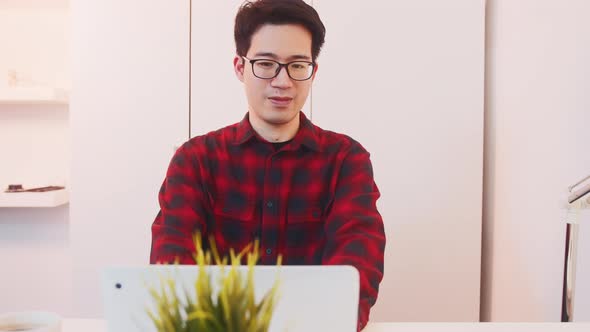 Young Positive Asian Guy Leaning Back in His Chair After Finishing Working on His Laptop at Home