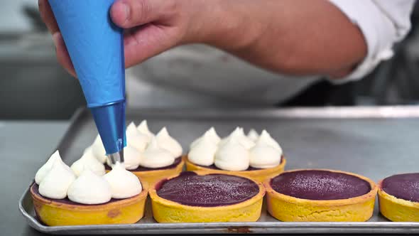 Pastry Chef Decorates Biscuit Tartlet with Cream From Pastry Bag, Close-up. Preparation of Cake at