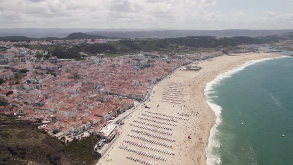 Aerial circular view of wide Nazarè beach. Portugal. Slow motion