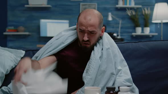 Close Up of Sick Man Blowing Runny Nose with Tissues