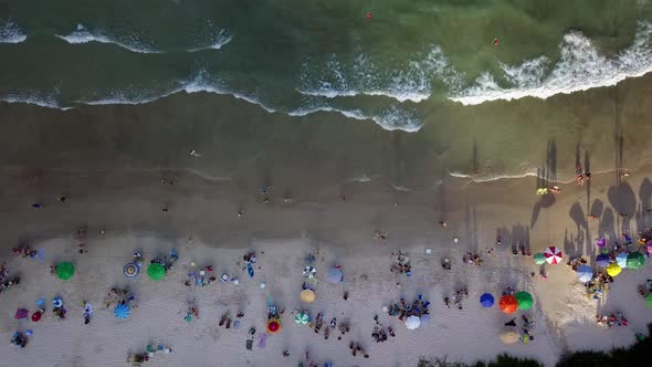 Aerial flying over Bombas beach full of tourists at golden hour in Brazil. Dolly right