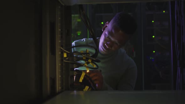 African american male computer technician using smartphone working in business server room