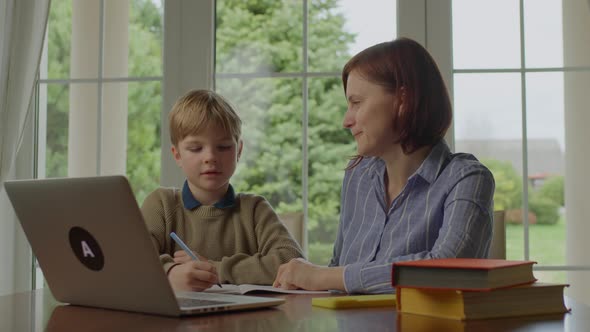 Young Mother Making Online Homework with School Kid at Home