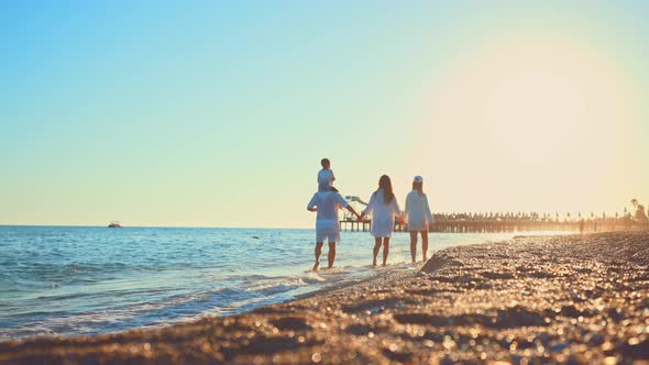 Happy Family Together Walk Holding Hands on Water on Sea Near Sandy Beach at Sunshine Day