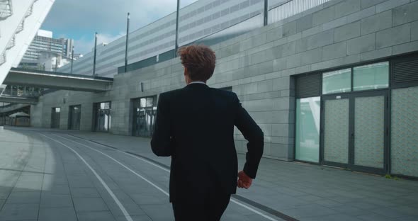 Back View Redheaded Businessman Running Through Downtown to Get to His Office on Time