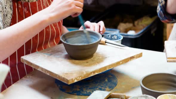 Female artist painting on earthenware bowl