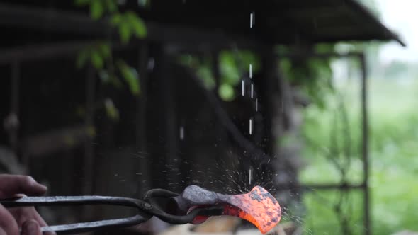 An Ax Heated By a Blacksmith is Kept on the Fire Under Raindrops