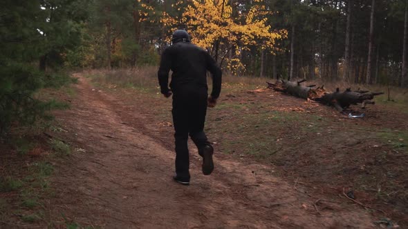 A Guy in a Black Dress is Training Runs Through the Forest Among the Pines Autumn