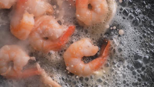 Cooking shrimp with butter on heated fry pan. Overhead shot. Slow Motion.