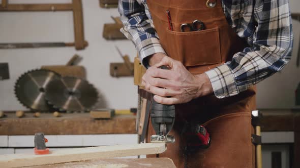 Carpenter is Sawing a Wood Plank with Electric Jig Saw Machine in Carpentry Workshop