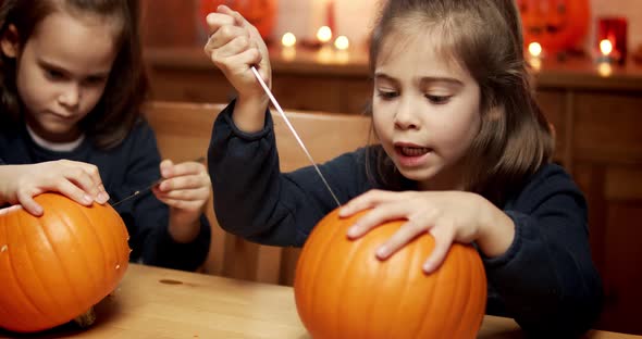 Two Cute Little Girls Are Cutting a Pumpkin on the Table for Halloween