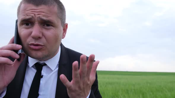 Young Businessman in Business Clothes Speaks Aggressively on a Mobile Phone