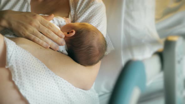 Mother breastfeeds and caresses newborn baby
